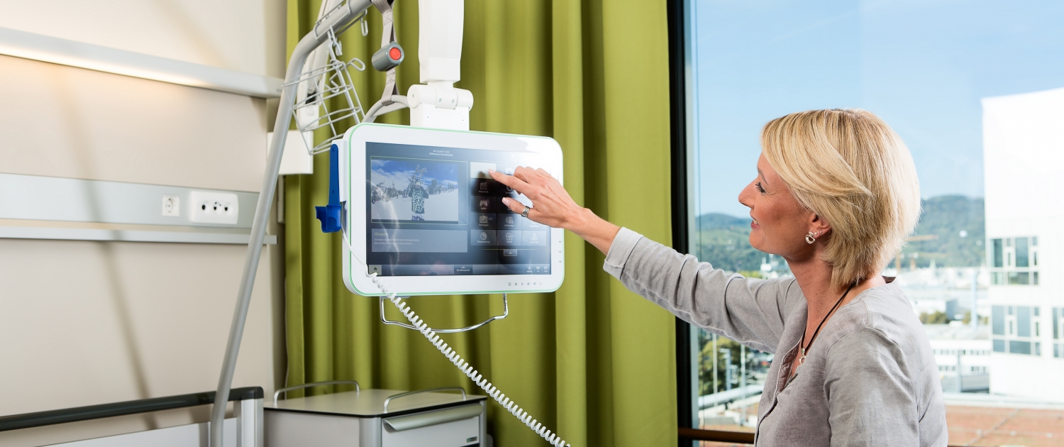 Patientin bedient ein modernes Gerät an ihrem Krankenbett